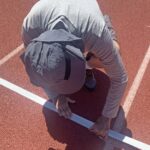 Jeff Davison secures tape marking start of 80-meter hurdles for certain men's and women's age groups.