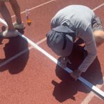 Jeff Davison secures tape marking start of 80-meter hurdles for certain men's and women's age groups.